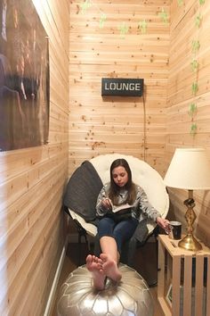 a woman sitting in a chair with her feet propped up on a stool next to a lamp