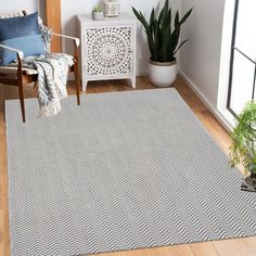 a living room area with a rug, chair and potted plant