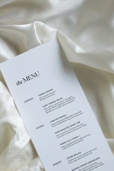 the menu is laid out on top of white satin material, with black writing in it