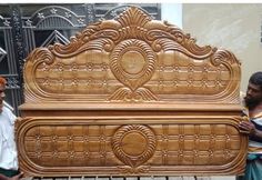 two men standing next to a carved wooden bed