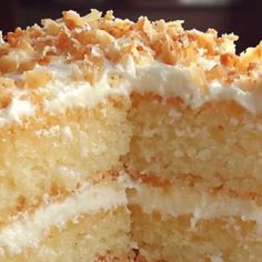 a close up of a cake with white frosting and coconut toppings on top