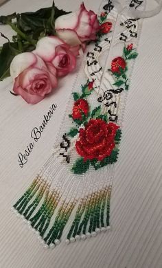 two roses are laying on top of a white table cloth with beading and beads