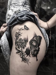 a woman's thigh with a skull and roses tattoo on it