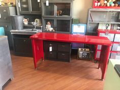 a red desk in the middle of a room with lots of shelves and other items