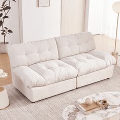 a white couch sitting on top of a rug in a living room next to a table