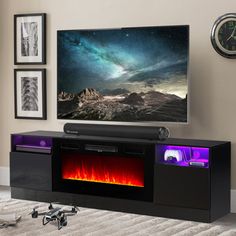 a flat screen tv sitting on top of a black entertainment center next to a fire place