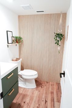 a white toilet sitting inside of a bathroom next to a wooden counter top under a mirror