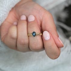 a woman's hand holding a ring with a blue stone