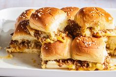 a white plate topped with sliders covered in cheese