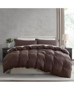 a bed with brown sheets and pillows in a room