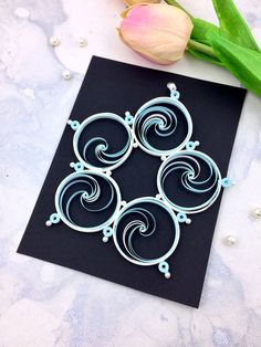 a card with four spirals on it next to a tulip and some pearls