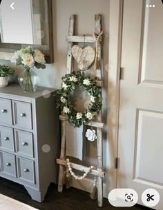 an old ladder is decorated with wreaths and flowers in front of a mirror on the wall