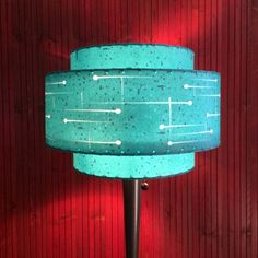 a lamp that is on top of a metal pole in front of a red wall