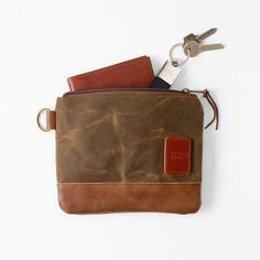 The go-to pouch for easy organization, this zipper pouch features a relaxed body that fits in small spaces, such as in your luggage or weekender bag. Crafted with waxed canvas, featuring leather and nylon details, this bag develops personality with use due to the patina. Keep your small essentials in this pouch with the option to clip it onto your bag for added storage. Add a heat stamped monogram to give it a personalized touch.   The material we use to make this bag is Haley Stevenson waxed canvas. Lined with a soft tartan interior. The bottom of the pouch is made with North American Cowhide leather. Vegetable tanned leather embossed logo on front.  All our bags are handmade in the USA and designed with care and attention to detail. The pouch measures approximately 8" wide X 6" tall Brown Pouch With Pockets For Everyday Carry, Brown Wallets With Zipper Pocket For Everyday Use, Functional Brown Pouch For Everyday Use, Everyday Pouch Wallet With Pockets, Practical Everyday Pouch With Zipper Pocket, Everyday Brown Pouch With Zipper Pocket, Rectangular Wallets With Waxed Finish For Everyday Use, Practical Wallets With Zipper Pocket For Everyday, Brown Pouch With Cell Phone Pocket For Everyday Carry