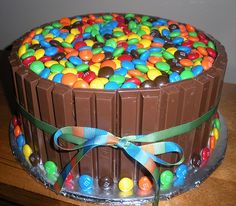 a large chocolate cake with candy and candies on the top, decorated with ribbon