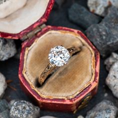 an engagement ring sits in its box on some rocks