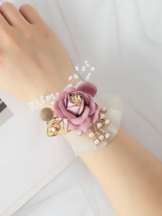 a close up of a person's arm wearing a bracelet with flowers and pearls