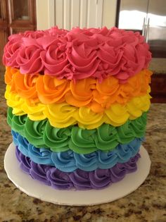 a multi colored cake with icing roses on it's top and bottom layer