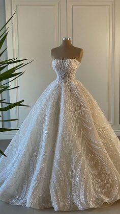 a wedding dress on display in front of a plant