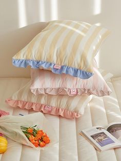 four pillows stacked on top of each other next to an open book and some flowers