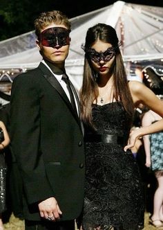 a man and woman dressed up in masquerades at an outdoor event, posing for the camera