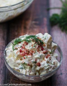 a glass bowl filled with potato salad on top of a wooden table