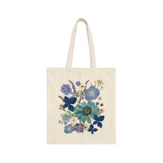 a tote bag with blue flowers and leaves on the front, in white background