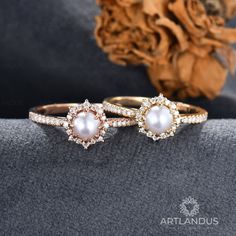 two gold rings with white pearls and diamonds on the side, one is in front of a flower