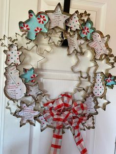 a wreath made out of cookie cutters and ribbon hanging on the front door to celebrate someone's special occasion