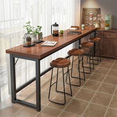 a long table with four stools next to it in front of a large window