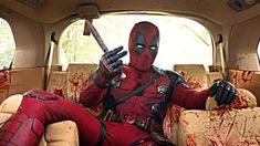 deadpool sitting in the back seat of a car