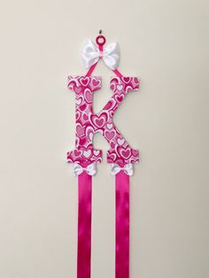 the letter k is decorated with pink and white ribbon