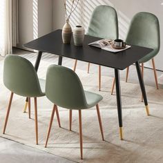 a black table with four green chairs and a vase on it in front of a window