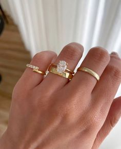 a woman's hand with two gold rings and a diamond ring on her finger