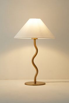 a table lamp with a white shade on it's base and a light bulb in the shape of a spiral