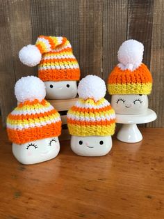 four knitted hats sitting on top of each other in front of a wooden wall