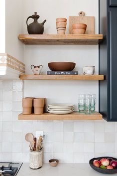 the shelves in the kitchen are filled with bowls, plates and utensil holders