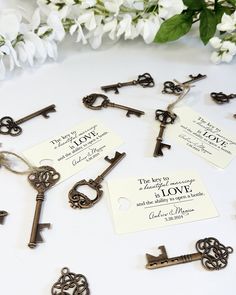 there are many keys on the table with some tags attached to each key and flowers in the background