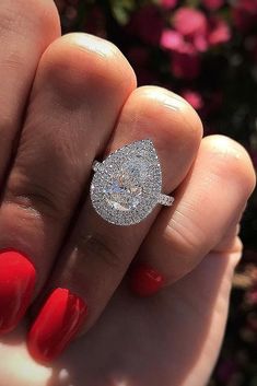 a woman's hand holding a diamond ring with red fingernails and nails on it