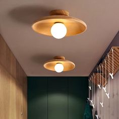 two circular lights hanging from the ceiling in a room with green walls and wood flooring