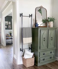 a green cabinet sitting in the middle of a room next to a mirror and door