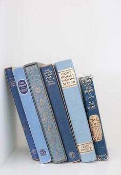 four books are lined up in a row on a white surface, one is blue and the other is yellow