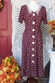 Beautiful floral acetate/rayon dress bestowing white flowers on a burgundy background make this dress a perfect tea party, garden party dress, for office, secretary, academia, church wear, etc.! Dress bestows a v-neckline with lacey off white collar, padded shoulders, short sleeves, large pearly front button closure, has a lace up back for a more fitted waist style that flares out around hips and is around calf length depending on your height. Dress is in excellent vintage condition showing minimal wear for its age. Please seem all photos as this is part of description. Tag states this as being a size 11 / 1 2, but this is vintage sizing so please check all measurements for best fit. Pictures were taken using a size 8 dress form and it fit this size quite nicely. Measurements are taken wit Ladies Tea Party, Office Academia, Dress For Office, Ladies Tea, Victorian Fashion Dresses, Tee Party, Burgundy Background, Party Garden, Garden Party Dress