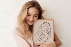 a woman holding up a drawing of a mother's face in front of her face