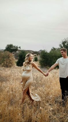 a man and woman holding hands in a field