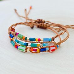 three bracelets with multicolored beads are sitting on a white surface and tied together