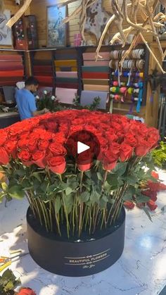 a large vase filled with red roses on top of a table