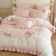 a bed with pink comforters and pillows on it