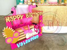 there is a pink and gold birthday card on the table next to a sign that says happy birthday