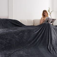 a woman sitting on a couch under a blanket